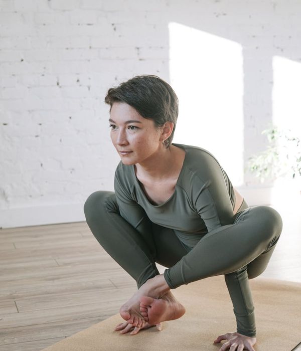 Woman in a calm, focused pose in a bright, airy room.